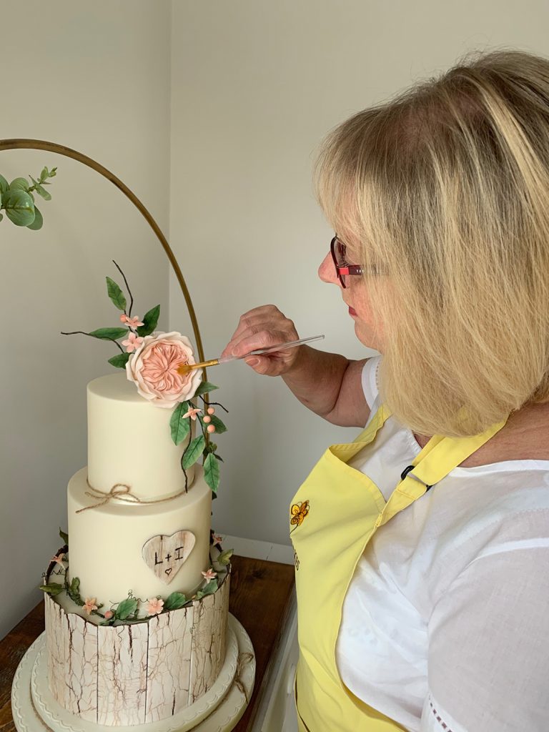 wedding planning lady decorating cake painting sugar flowers