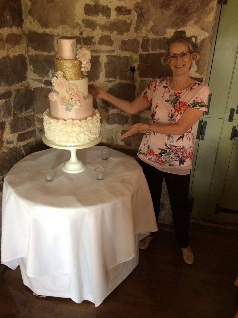 wedding planning lady with 5 tier wedding cake pink flowers white ruffles