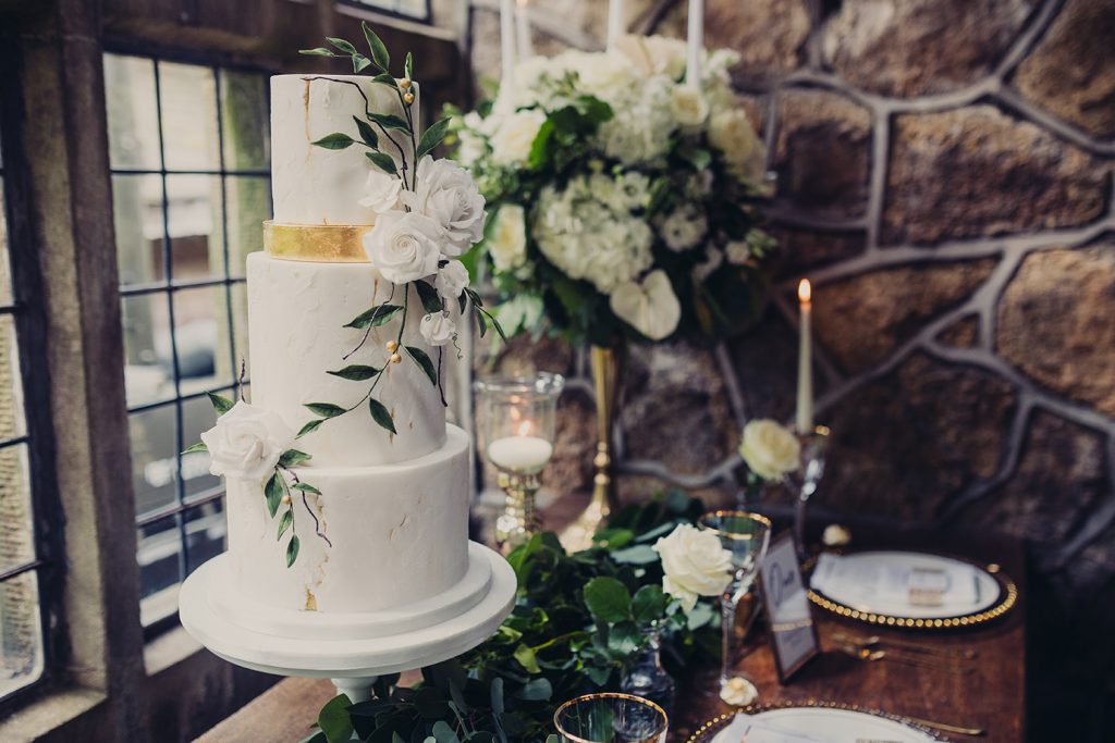 wedding planning white 3 tier cake gold foil white roses leaf trail floral foliage background