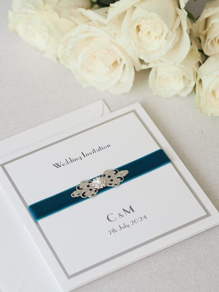 front of pocketfold wedding invitation white silver edge teal velvet ribbon crystal embellishment