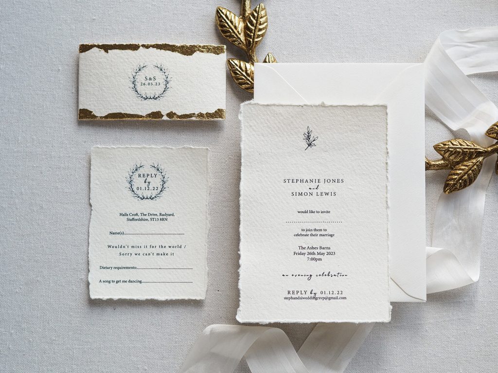 handmade paper wedding invitation suite flat lay rsvp invitation bellyband gold leaf edge silk ribbon